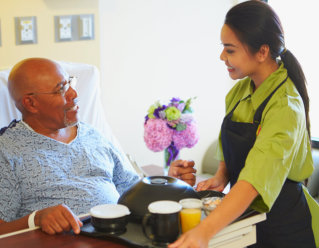 caregiver serving meal to elderly man
